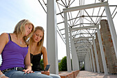 Zwei junge Frauen lesen eine SMS auf dem Handy, Hofgarten, München, Oberbayern, Bayern, Deutschland