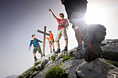 Hikers arriving summit cross, Wetterstein range, Bavaria, Germany