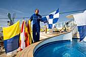 A sailor with signal flags at the deck of cruise ship AidaDiva