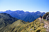Trekker auf dem Kepler Track unter blauem Himmel, Blick auf Kepler Mountains, Fiordland Nationalpark, Südinsel, Neuseeland, Ozeanien