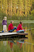 Three persons on a jetty, two are fishing, Vasterbotten, Sweden (July 2005)