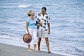 Senior couple walking hand in hand at beach