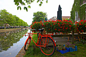 Red bicycle standing at the banks of a gracht canal, Weesp, Netherlands, Europe