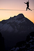 Mann balanciert auf einem Seil im Abendrot, Slackline in den Bergen, Oberstdorf, Bayern, Deutschland