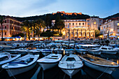 Boote im Hafen und das beleuchtete Hotel Palace am Abend in der Altstadt, Hvar, Insel Hvar, Dalmatien, Kroatien, Europa