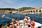 Touristen sitzen im Bug eines Bootes mit Blick auf Hvar, Dalmatien, Kroatien, Europa