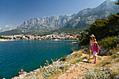 Frau und Kind gehen auf Küstenweg im Sonnenlicht, Blick auf Makarska, Dalmatien, Kroatien, Europa