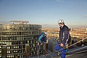 industrial climber working on Kollhoff-Tower with DB tower in background, Berlin