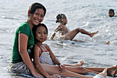 Junge Frau mit Mädchen sitzt im Wasser, Ost Bali, Indonesien, Asien