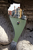Gondola on the Grand Canal glimpsed through the balustrade of the Rialto Bridge, Venice, Italy.