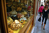 People walking past window of sweet and cake shop in Venice, Italy.