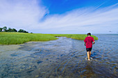 15 year old boy walking in the water at Rock Harbor, Orleans, Cape Cod, Massachusetts, USA