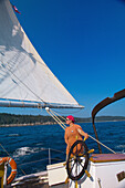 Crew member steers the Schooner Nathaniel Bowditch on Penobscot Bay, Maine USA
