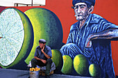 Street seller in front of mural painting, Santiago de Cuba. Cuba
