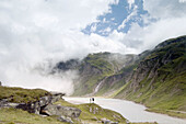 Two people before a alpine lake in the Hohe Tauern region of Austria