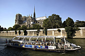 Notre-Dame Cathedral with a tour boat in River Seine in foreground. Paris. France