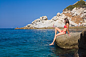 Woman sunbathing on rock near Sant' Andrea, Elba, Italy