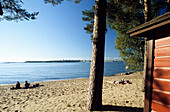 Menschen am Strand der Insel Pihlajasaari im Sonnenlicht, Finnland, Europa