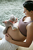 Pregnant woman with stuffed toy on belly