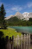 Wooden fence in front of the Antholzer lake in idyllic mountain scenery in the sunlight, Val Pusteria, South Tyrol, Italy, Europe