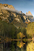 Ein herbstlicher Wald spiegelt sich in einem Bergsee, Völs am Schlern, Südtirol, Italien, Europa