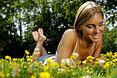 Woman lying in a meadow full of flowers, Relaxation, South Tyrol, Italy