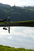 Frau mit Golftasche an einem Teich auf dem Golfplatz Kastelruth Seiser Alm, Schlern, Südtirol, Italien, Europa