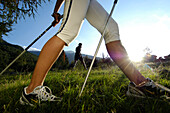 Nordic Walking, die Beine einer Frau auf einer Wiese im Sonnenlicht, Vinschgau, Südtirol, Italien, Europa