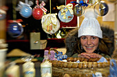 Lächelnde Frau an einem Verkaufsstand für Christbaumkugeln auf dem Weihnachtsmarkt in Kastelruth, Eisacktal, Südtirol, Italien, Europa
