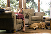 Man sleeping on chair with dogs sleeping on floor next to him