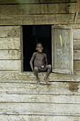 Boy sitting in the window and smiling, Indonesia