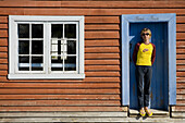 Woman standing in front of a wooden house.