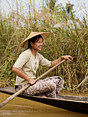 Burmese woman paddling her boat on Inle Lake in Myanmar