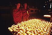Buddhist monks lighting candles in Bouddhanath stupa. Kathmandu, Nepal