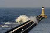Waves breaking over a breakwater at Tynemouth, England, UK