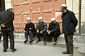 Muslim men sit outside the beautiful old mosque in the old muslim quarter of Xian, Shanxi, China