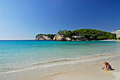 Small girl playing on the beach, sandy beach and turquoise sea at Cala Galdana, Minorca, Balearic Islands, Spain