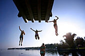 Mädchen springen von einem Sprungbrett in den Ammersee, Utting, Bayern, Deutschland