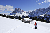 Backcountry skier, snow-covered alpine lodge in background, Grosser Gabler, Eisacktal, Dolomites, Trentino-Alto Adige/Südtirol, Italy