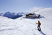 Backcountry skier, alpine hut Plattkofelhuette in background, Langkofel range, Dolomites, Trentino-Alto Adige/Südtirol, Italy