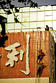 Workers repairing sign. China.