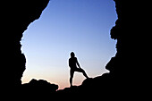 Silhouette of person at the entrance of a cave