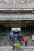 Betende Taoistin vor dem Eingang des Bao-an Tempel, Stadtteil Shida, Taipeh, Taiwan, Asien