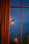 Curtain at a window with view at street lanterns at night, Cinema International at night, Berlin, Germany
