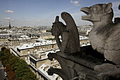 France. Paris. Gargoyles on the Galerie des Chimeres of Notre_Dame Cathedral with the view of La Cite in the background.