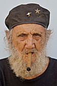 An old Cuban man wearing a beret and smoking a cigar.