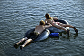 Young tourists swimming on old wheels in a river in Vang Vieng, Laos