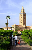 Familie in einem Park vor dem Minarett der Koutoubia Moschee, Marrakesch, Süd Marokko, Marokko, Afrika