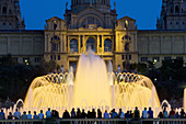 People gathered at illuminated fountain. National Palace and fountains. Montjuic. Barcelona. Spain