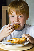 8 yr old boy eating croissants